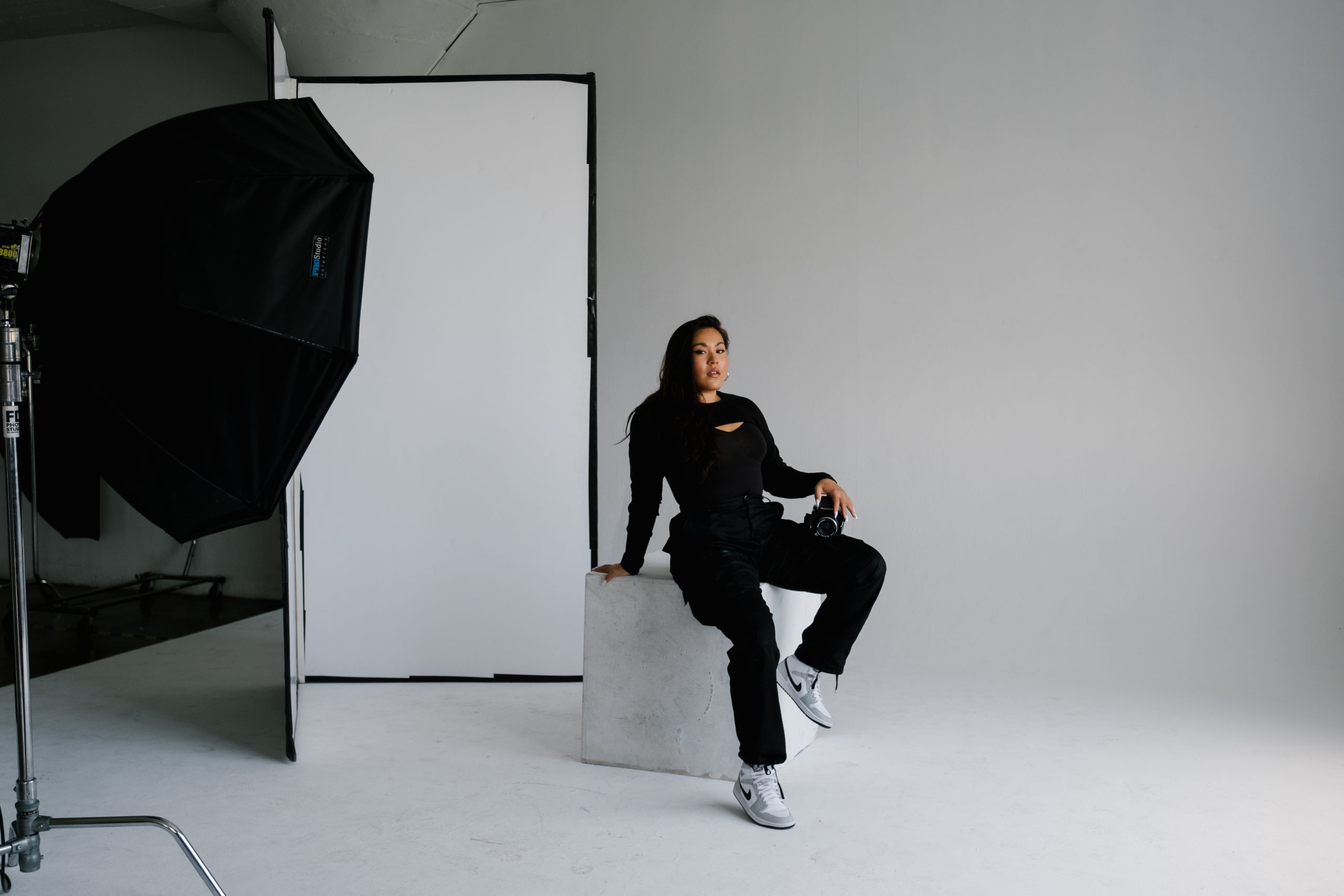Photographer sitting on white block in photo studio